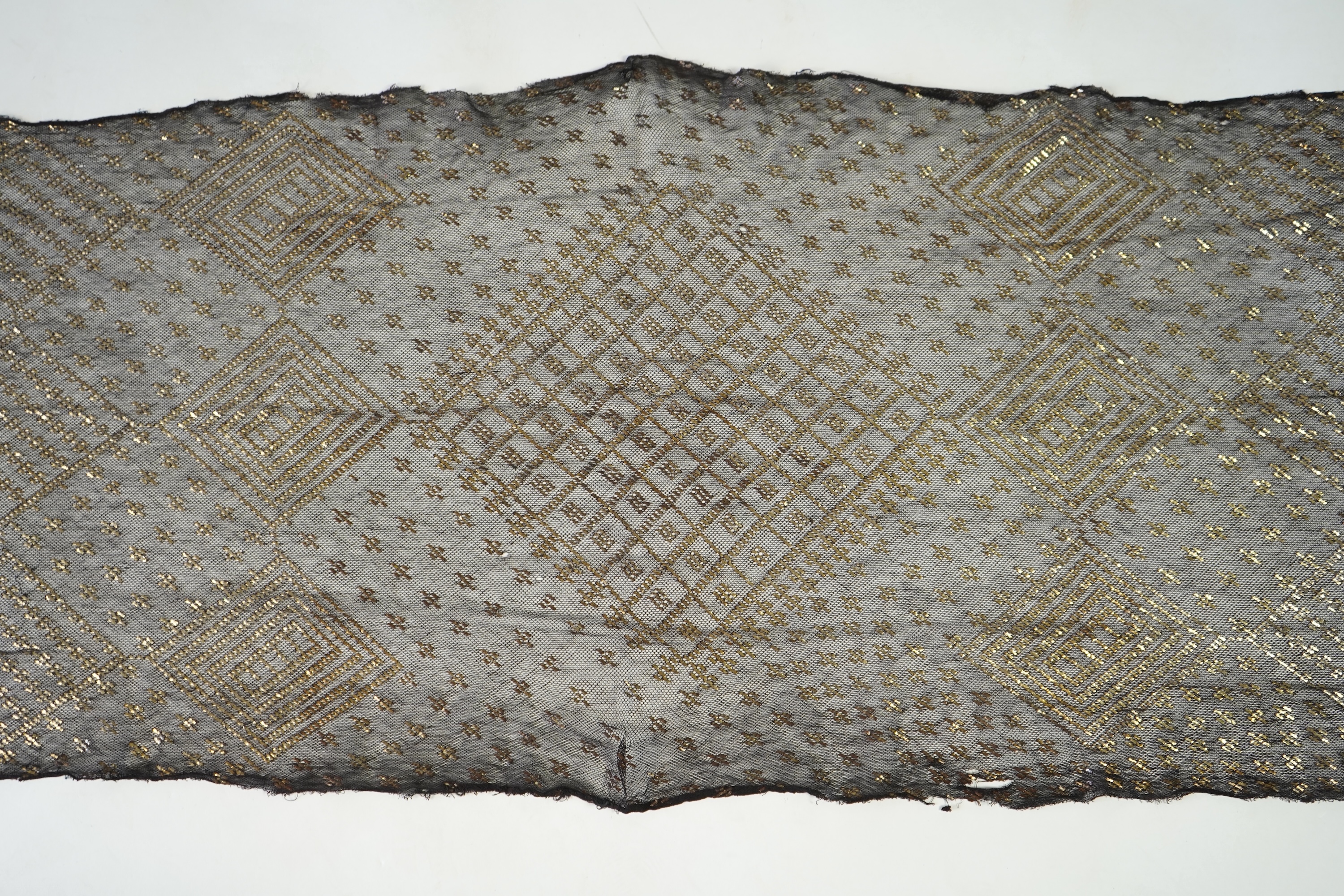 A 1930’s Egyptian decorative metal on black net evening stole. Approximately 218cm long. Condition - the rolled edges are frayed but the colour and design are intact.